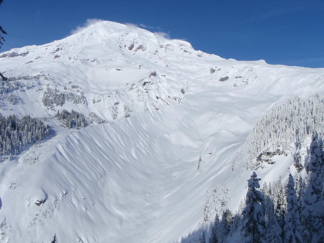 A snow-covered mountain peak with a blue sky in the background
