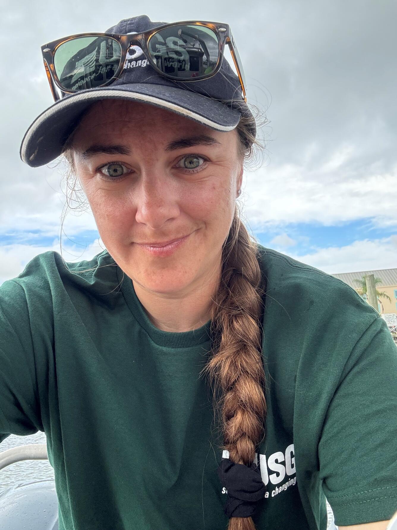 woman in USGS hat and shirt smiling outside