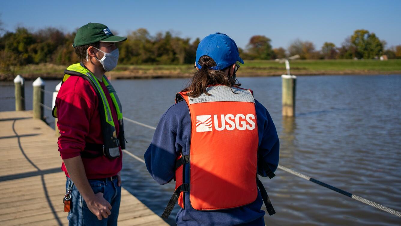 USGS hydrologic technicians stand on a dock above the Anacostia River at Bladensburg Waterfront Park in Maryland.