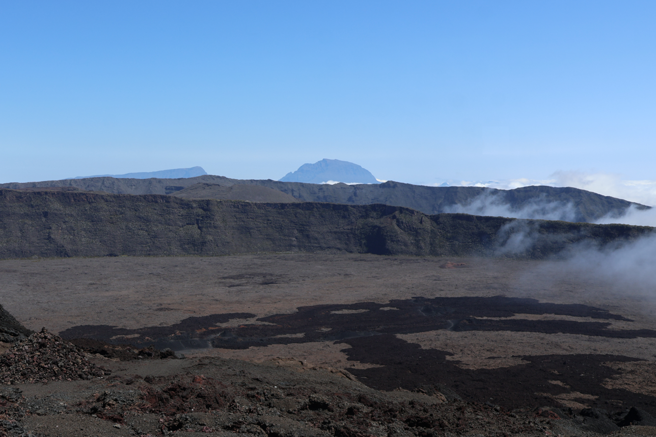 rocky cliffs with clouds and mountain visible in the background