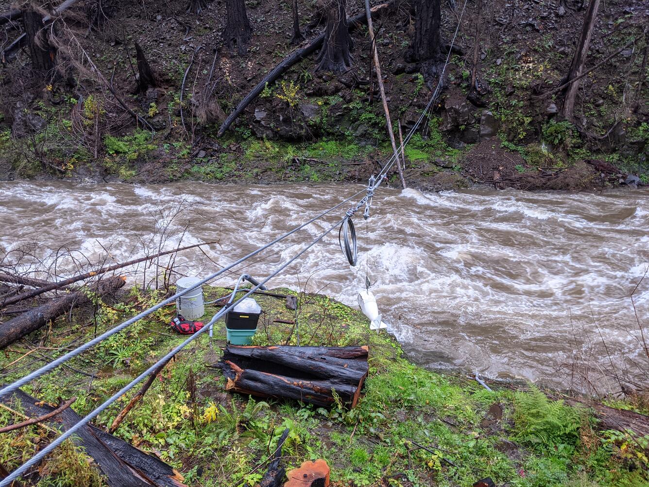 dark brown, turbulent water flows underneath the sediment sampler setup