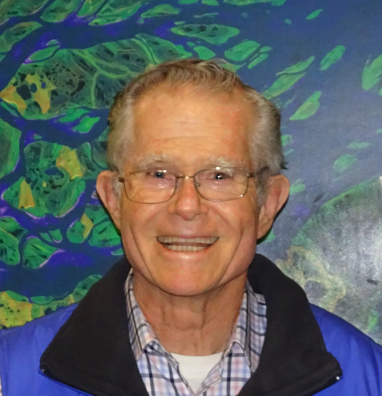 Headshot of a white-haired man wearing glasses, smiling broadly
