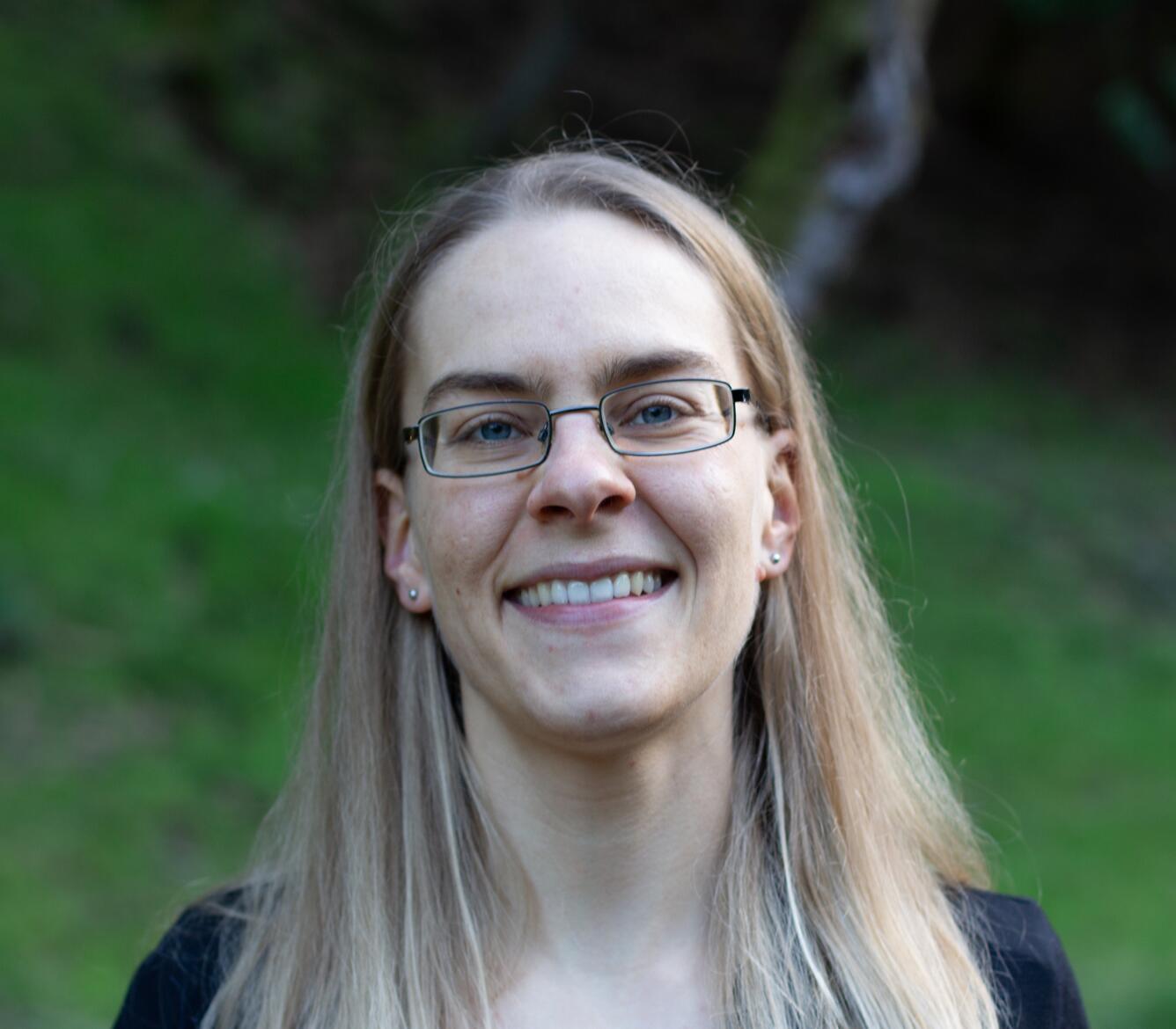 Headshot of a smiling blond-haired woman with glasses