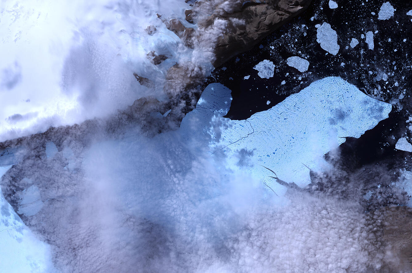 Satellite image of a glacier with chunks of ice in the water around the end of it
