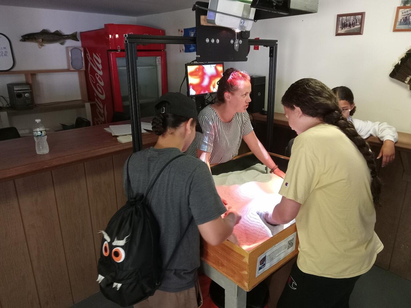 Person showing students augmented reality sandbox in room