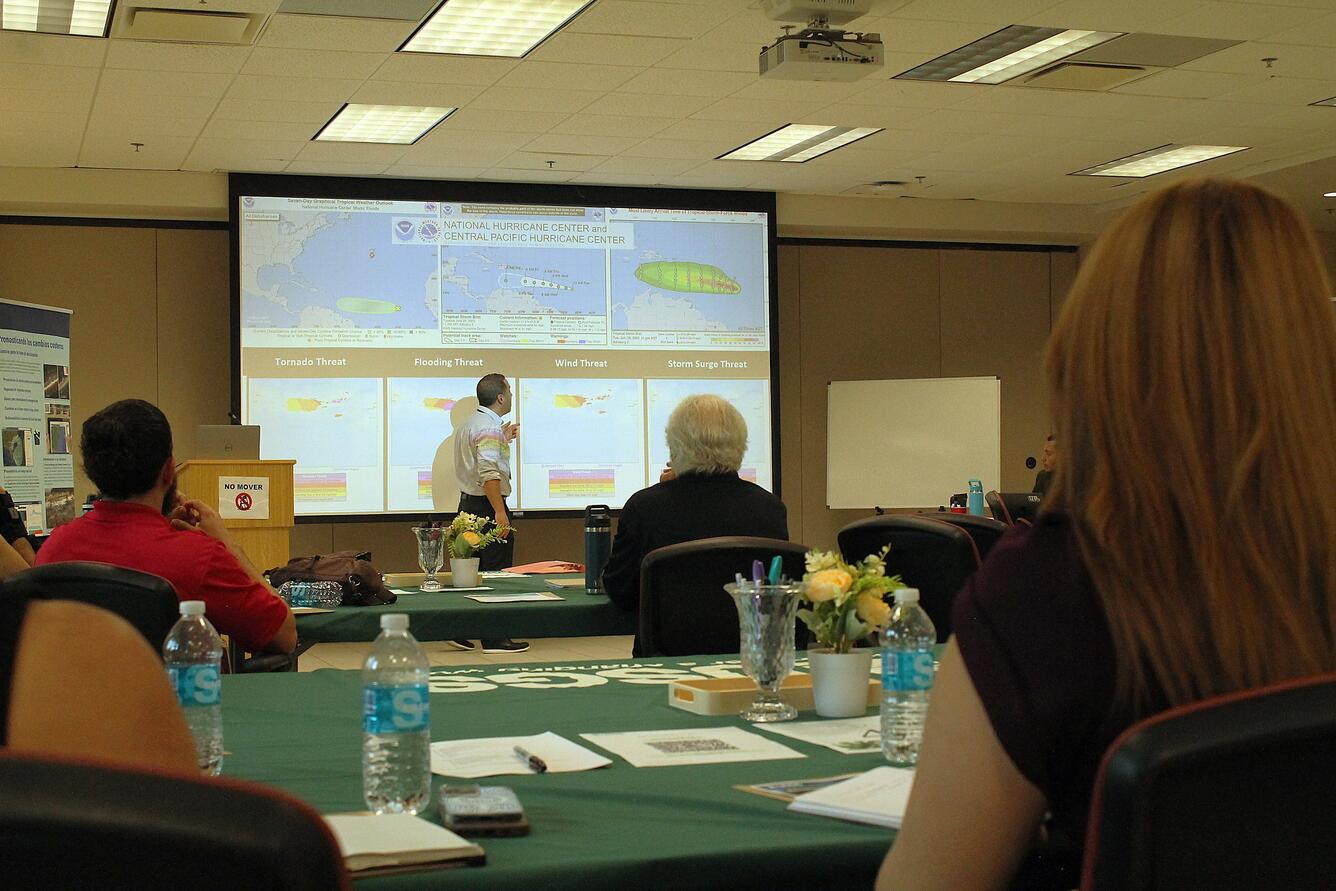 A representative from the National Weather Service presents while seated workshop participants observe the presentation.