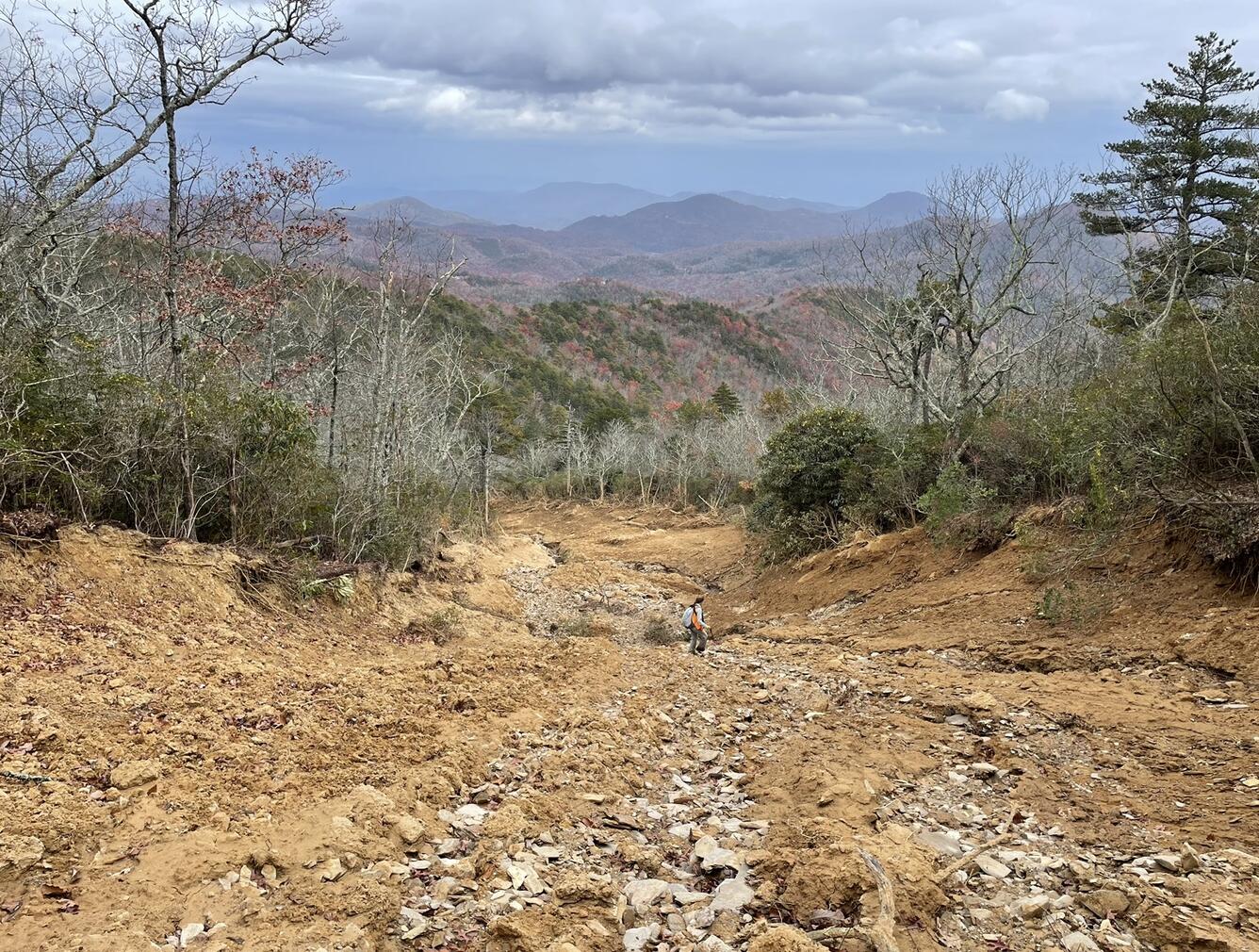 person stands on a hillslope covered with mud and rocks