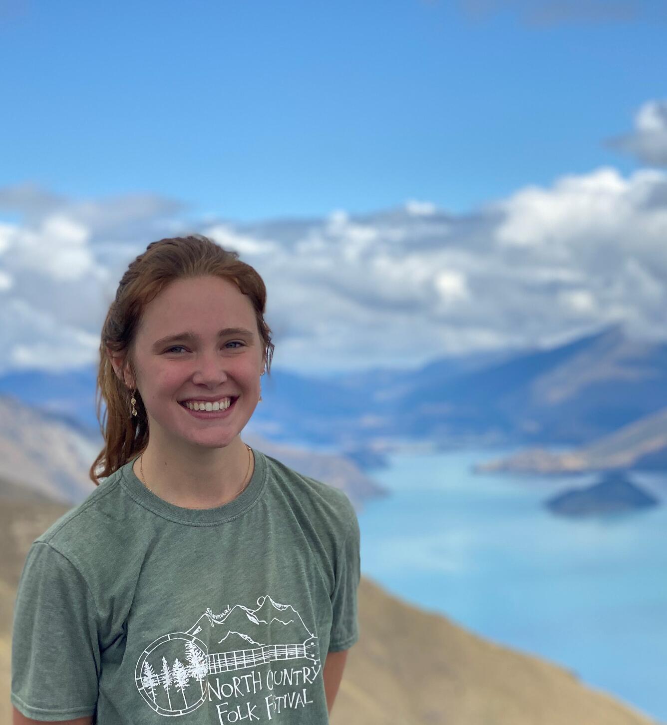 Close up photo of Hydrological Technician Eloise on mountain top. Water, mountain and clouds in the background. 