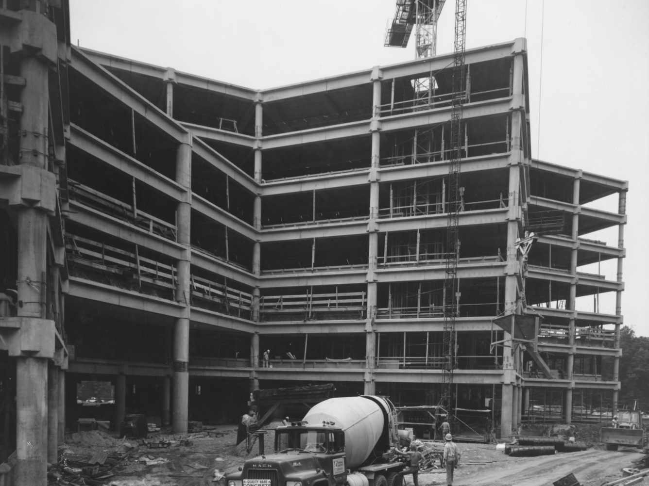 A black and white photo of the bare concrete and posts of the main building, forming the overall shape.