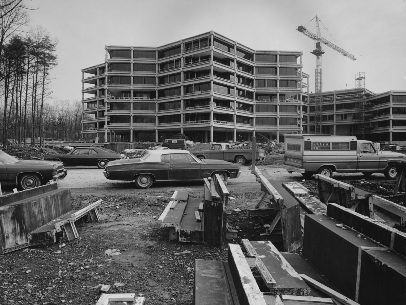A black and white photo of the building, with construction debris in front and a crane still working.