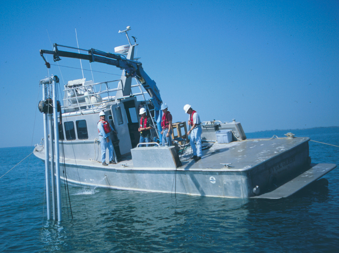 An instrument being deployed from a research vessel on the ocean under a blue sky