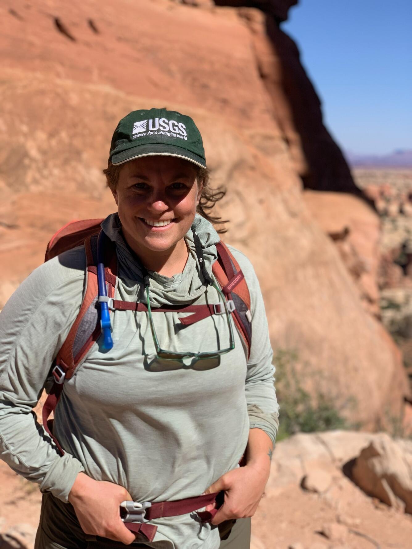 Staff profile photo of Rebecca Finger-Higgens, wearing a backpack in Canyonlands, UT during fieldwork