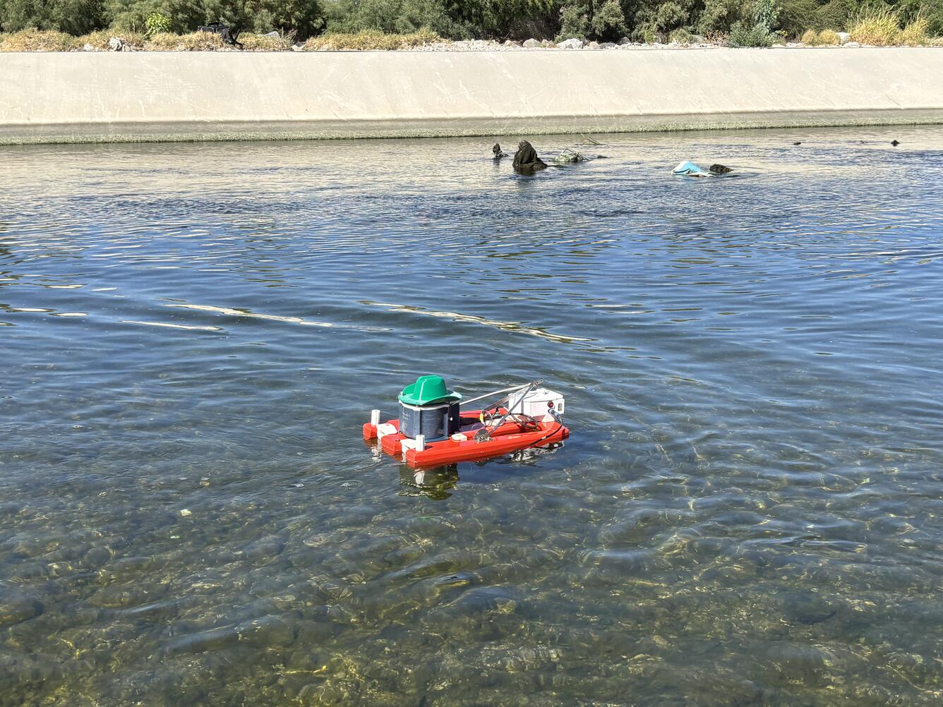 Bright red remote controlled ADCP boat floats in a canal at the Las Vegas Wasteway monitoring site.