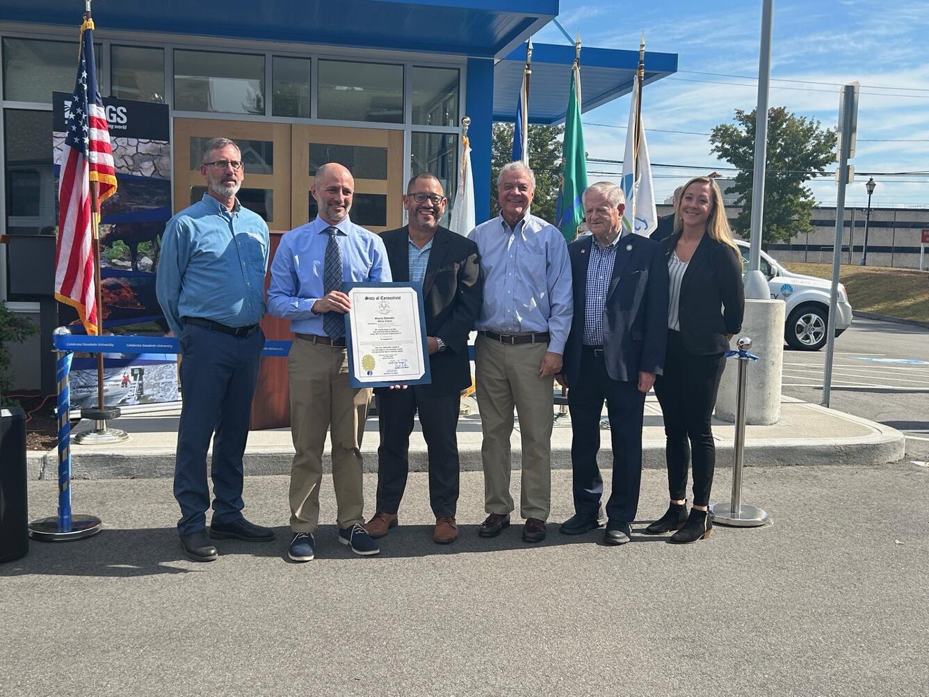 Men hold a sign in front of a building.
