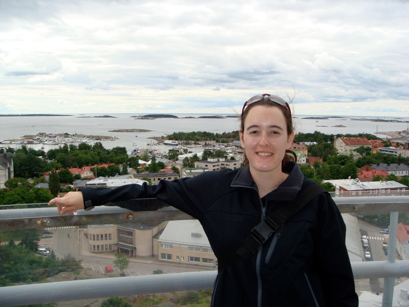woman with red hair, wearing glasses on her head and black sweatshirt, near water