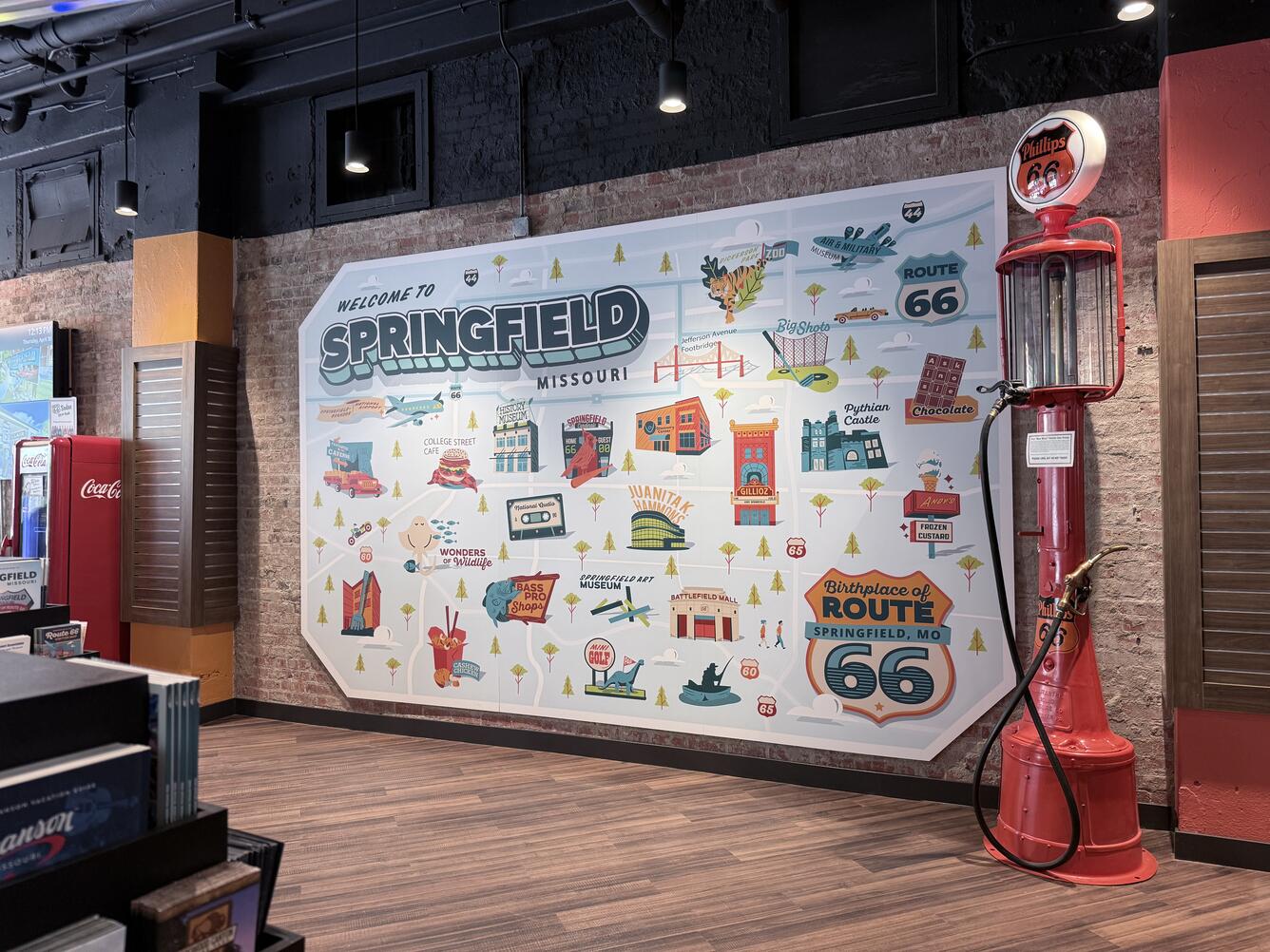 A large illustrated wall cartoon-style map and red vintage Phillips 66 gas pump against a wall