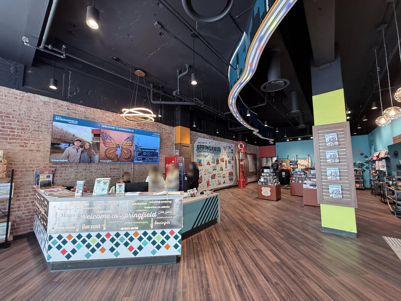 Wide view inside the visitor center, showing seating, merchandise displays, and a wall reading “Visit Springfield Missouri."