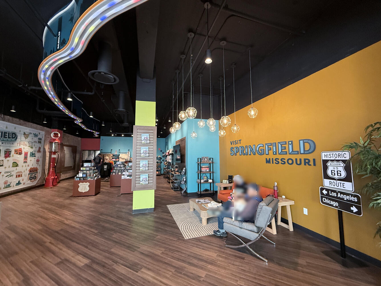 Wide view inside the visitor center, showing seating, merchandise displays, and a wall reading “Visit Springfield Missouri.” 