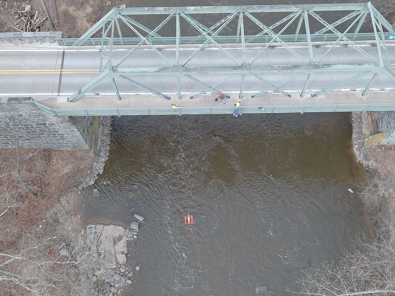 An aerial view of hydrologic technicians on a truss bridge above Brandywine Creek measuring streamflow with an ADCP.