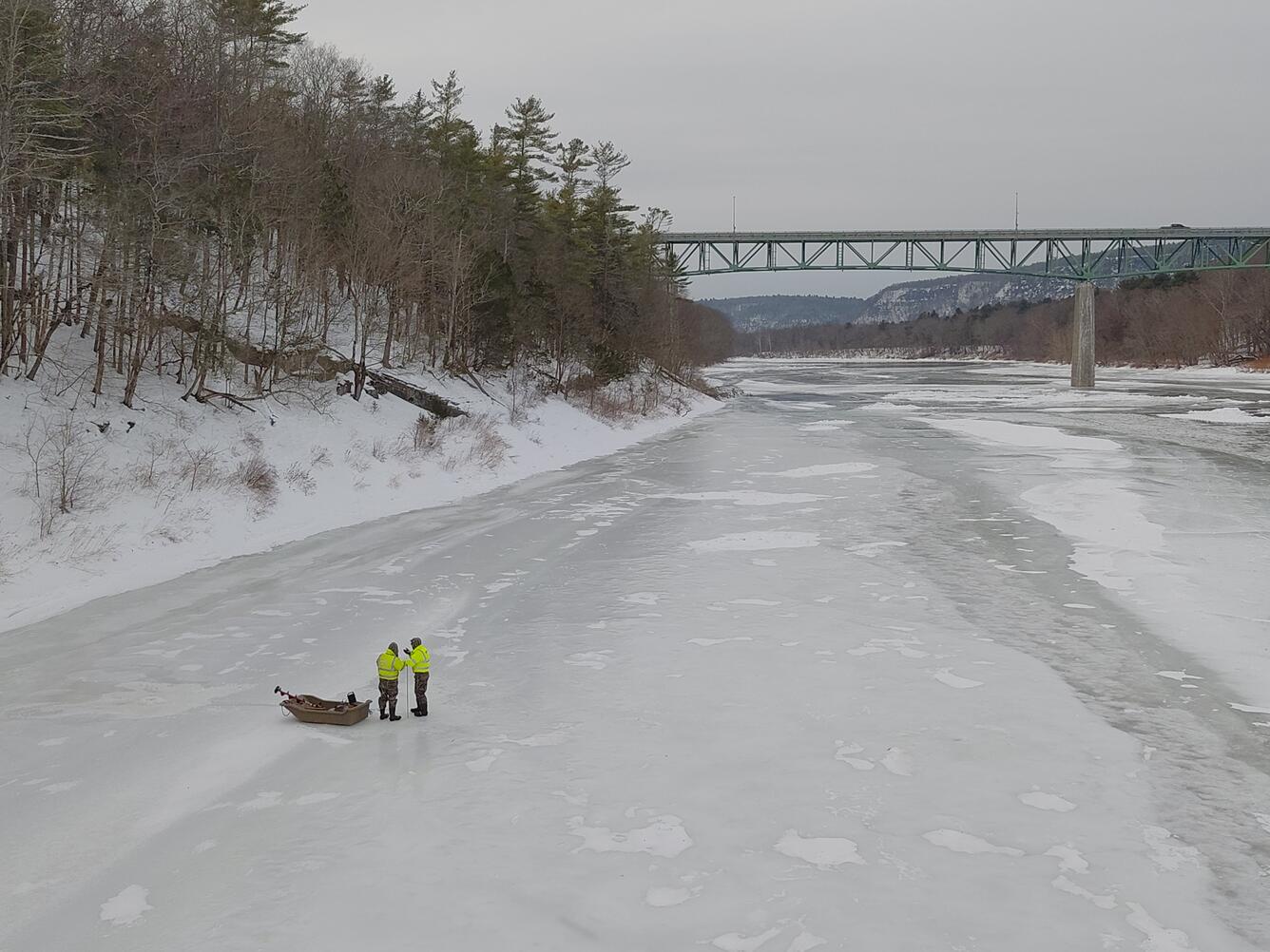 Two men standing next to an Ice Sled on the frozen Delaware River as they prepare to make a measurement