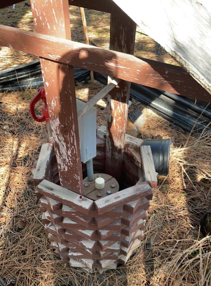 steel well casing with decorative cover. Spigot next to the well.