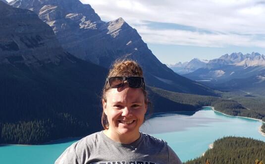 Woman standing in front of a mountain and lake