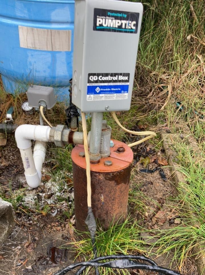rusty steel well casing and cap in a grass area