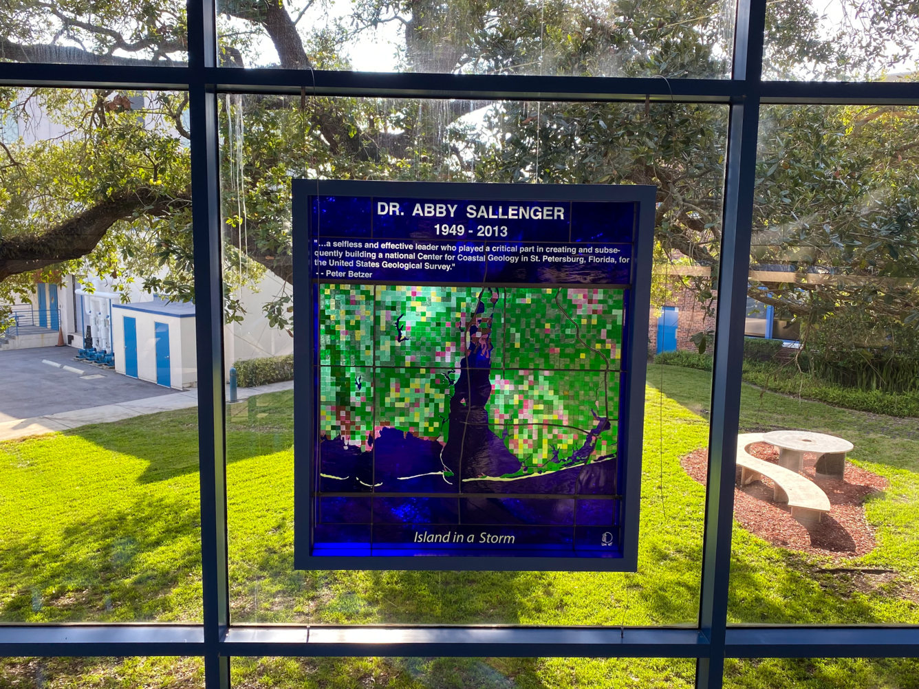 Stained glass art in window of coastal AL says, "Dr. Abby Sallenger, 1949-2013, Island in a Storm" 