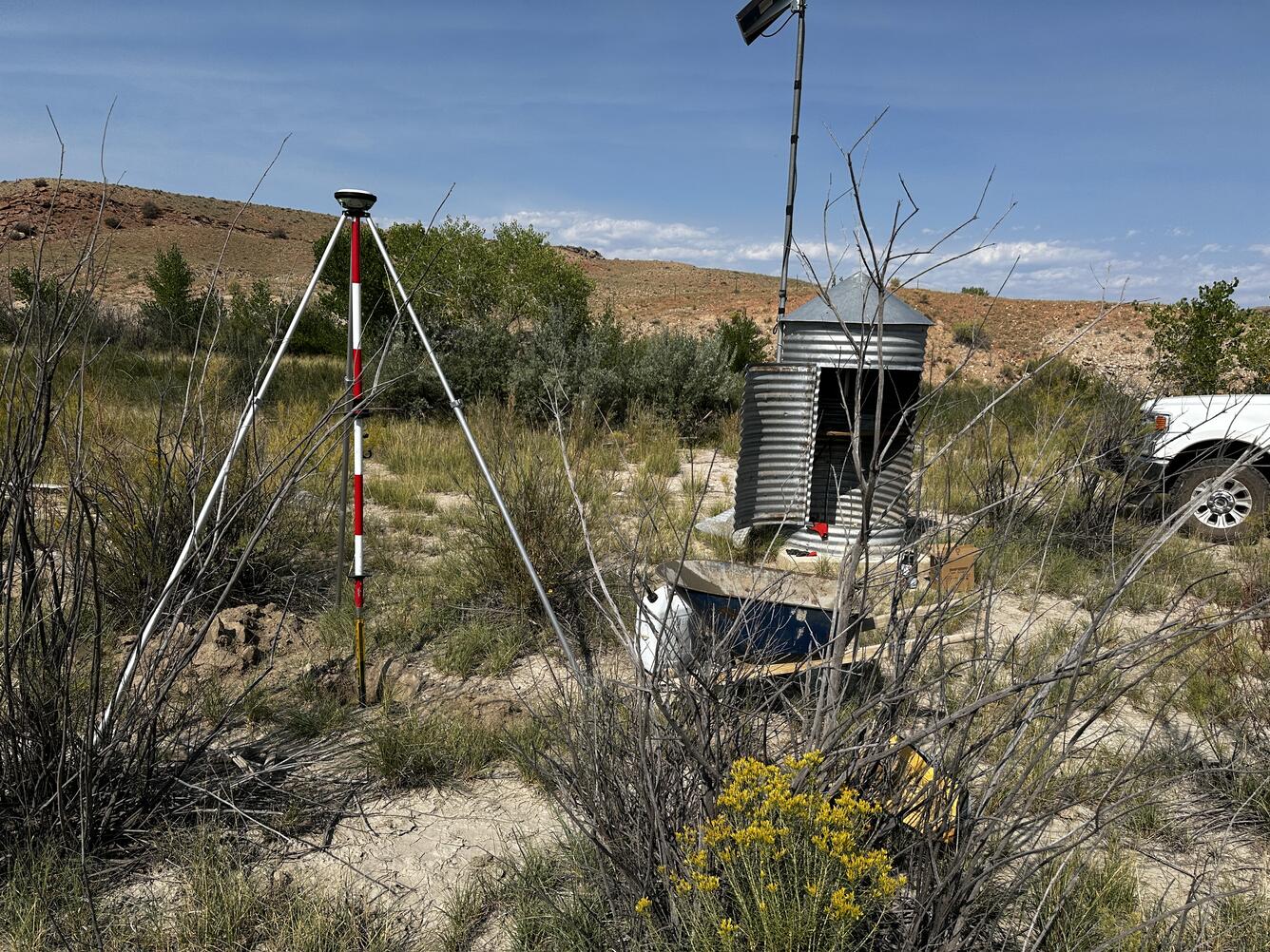 Gage house and tripod next surrounded by desert vegetation.