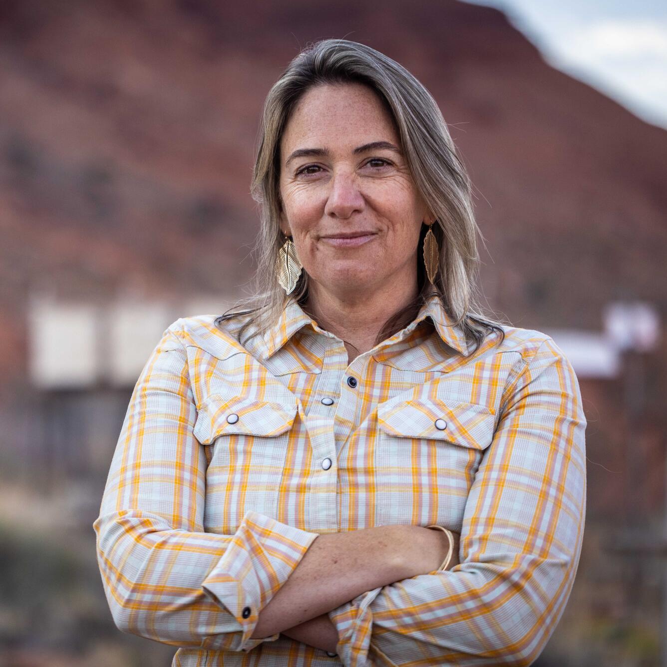 A smiling woman in a stands in a desert.