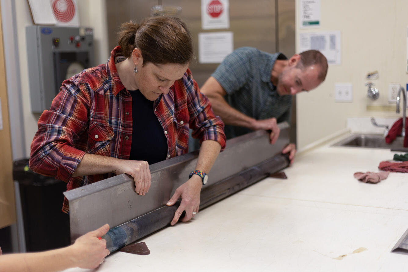 Scientists separating a sediment core split lengthwise
