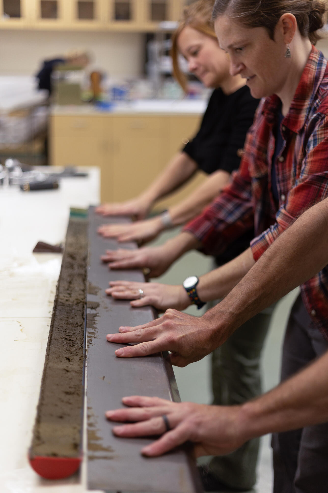 Scientists separating a sediment core split lengthwise