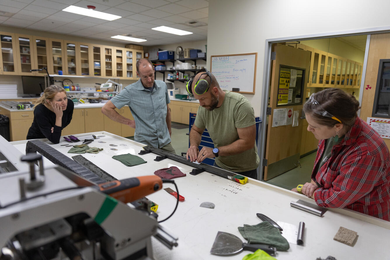 Scientists separating a sediment core split lengthwise