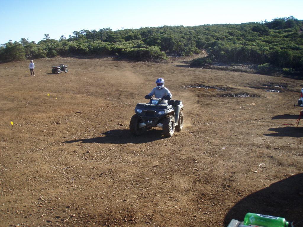 Person with helmet riding on top of a vehicle on the dirt