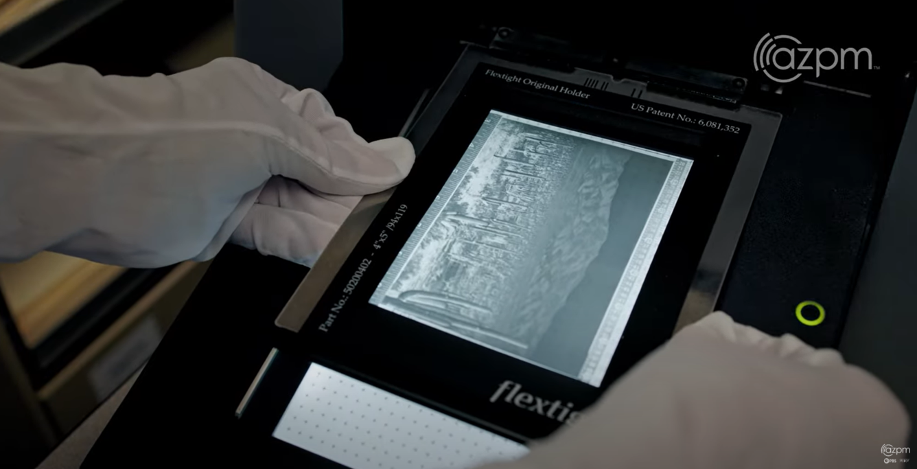 A person with archival gloves on handles film as it it scanned