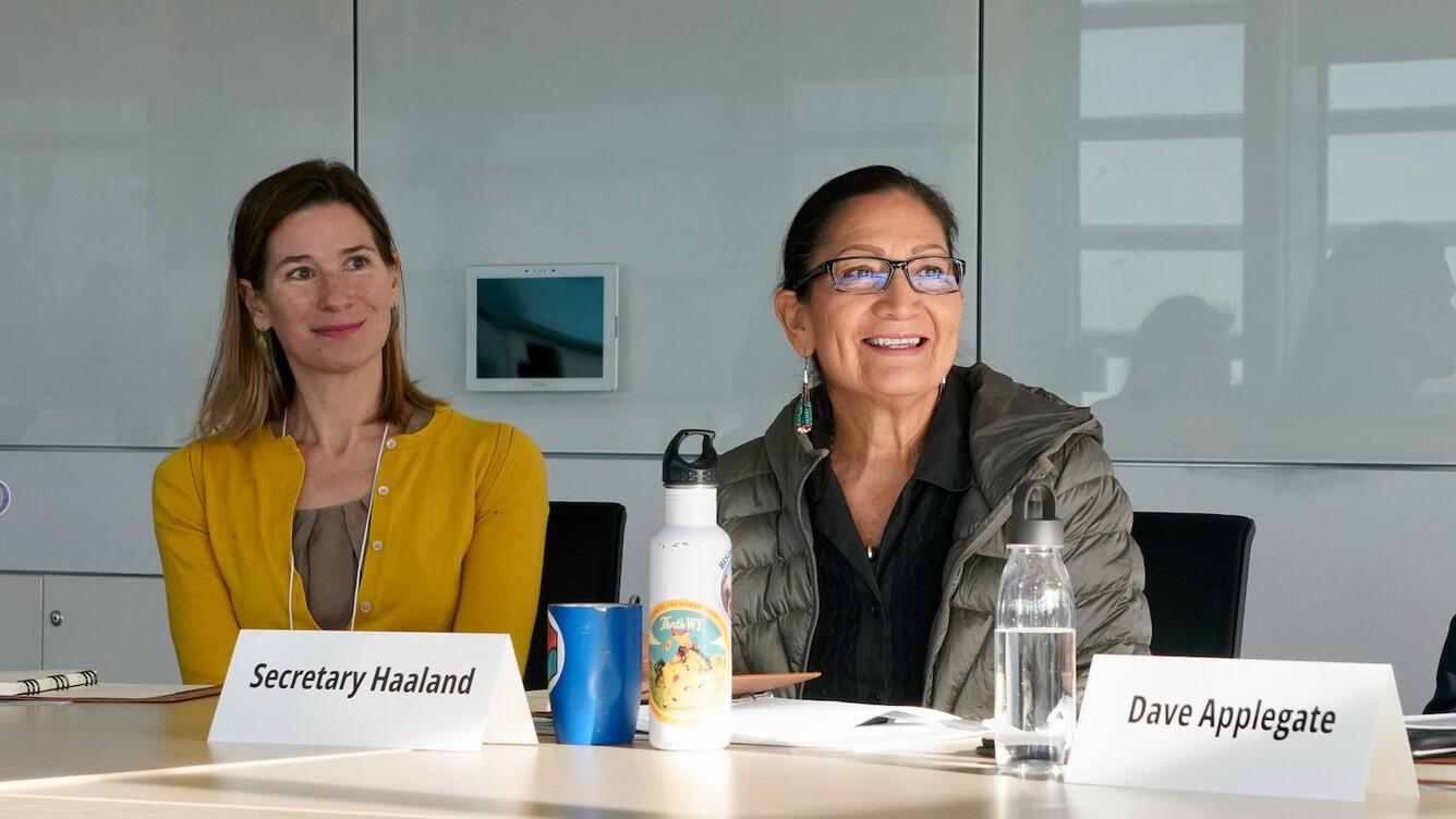Two women are sitting at a table during a conference. 