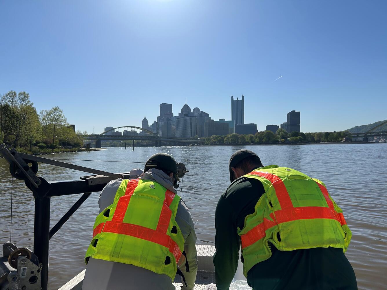 photograph of two men on a river with city skyline in background