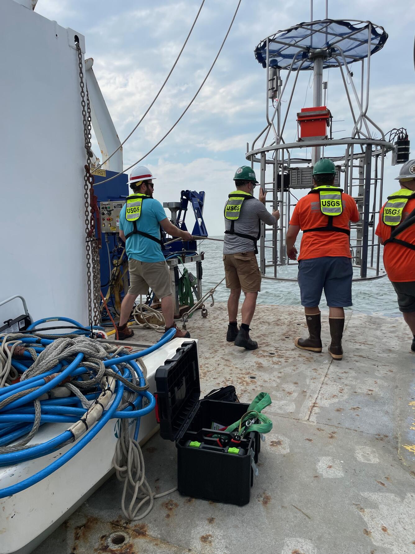 Three people on boat in the ocean working with a multicorer