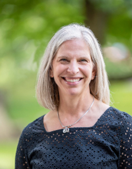 Profile photo for Stacy Curtis, a blonde woman in front of a green forested background.
