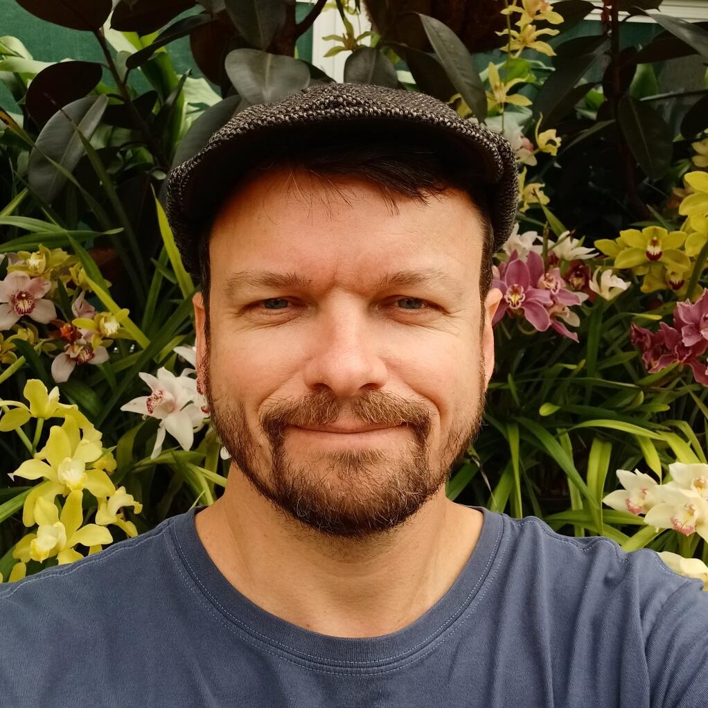 Man standing with leaves and flowers in background