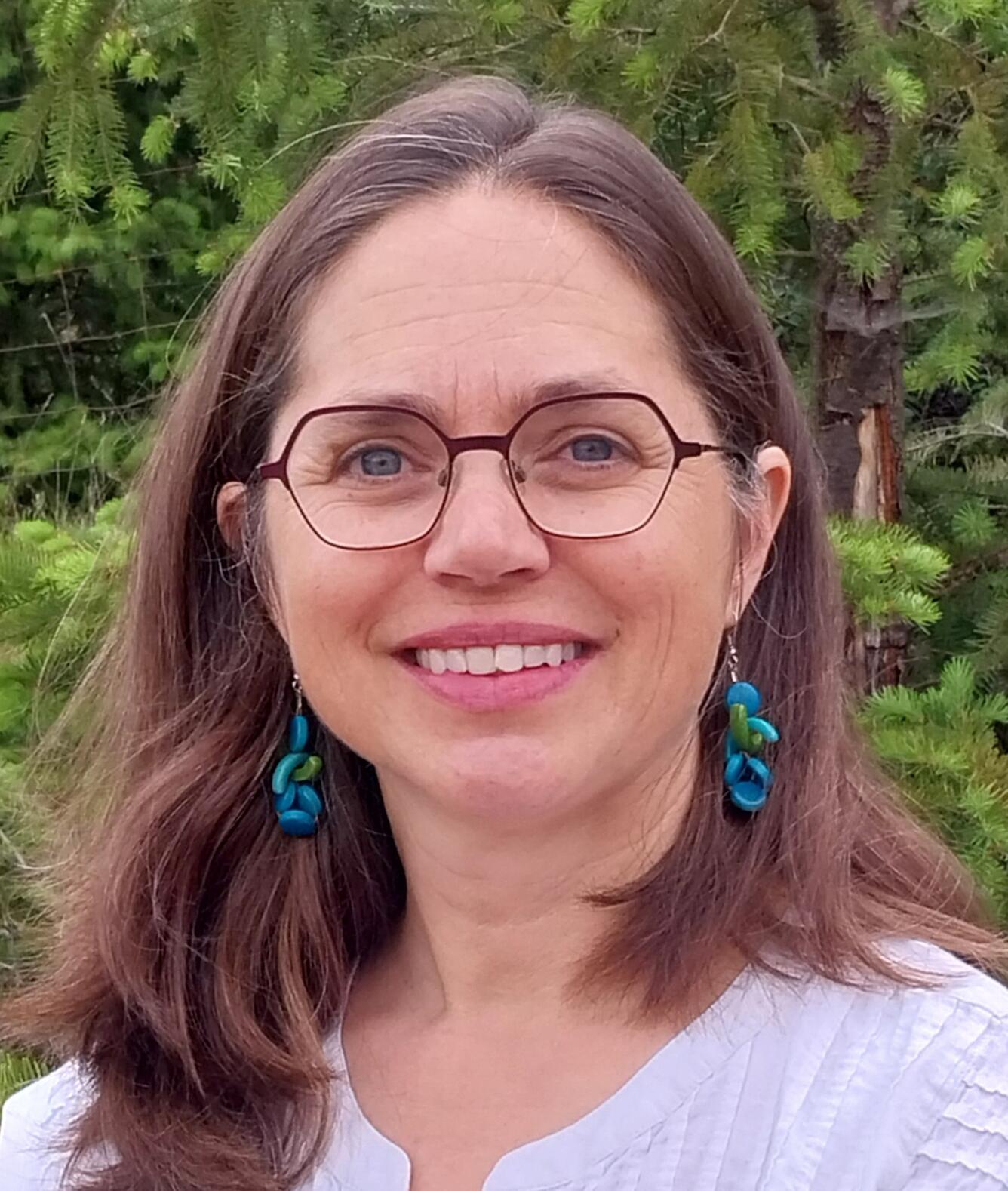 woman smiling headshot wearing glasses and blue earrings