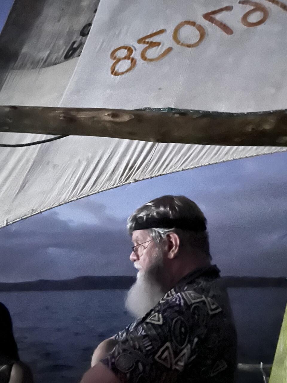 Man's profile below a sail staring at the sea