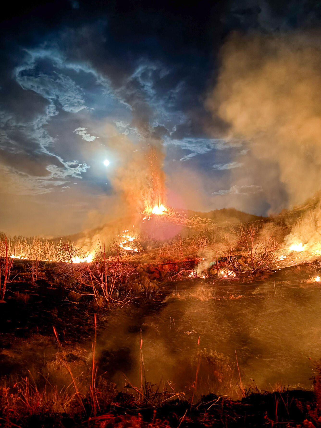 Fire on a mountain under a moon-lit night