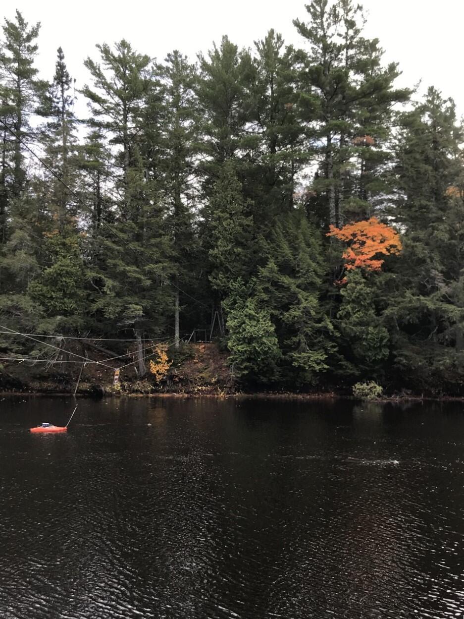 ADCP floating in river tethered to cable with fall foliage in background