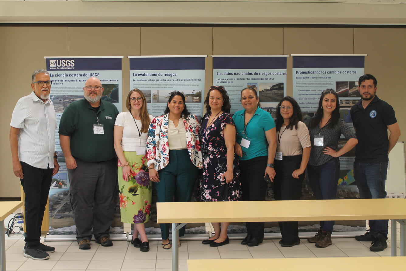 Nine team members from the Participatory Engagement workshops standing in front of four USGS banner stands.