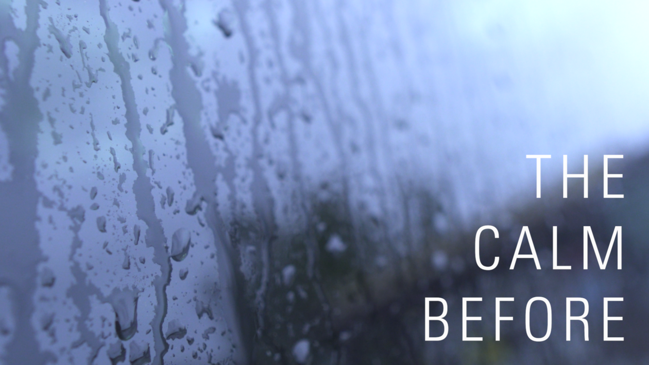 Water droplets streak down a glass window pane. Text superimposed on the image reads "The Calm Before".