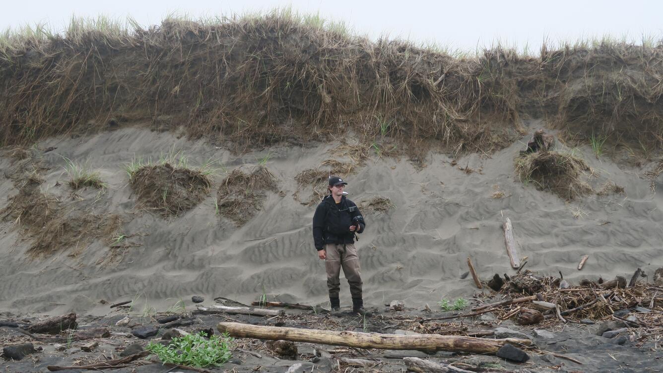 USGS Oceanographer Andrew Stevens performing a topographic survey at the base of an eroding dune