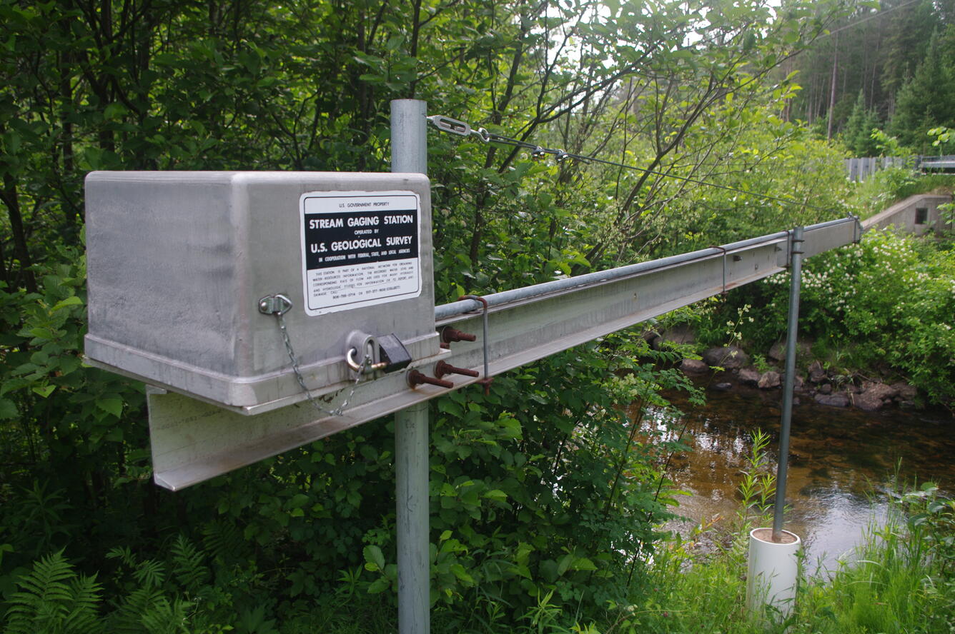 View of streamgage equipment on side of river with USGS signeage