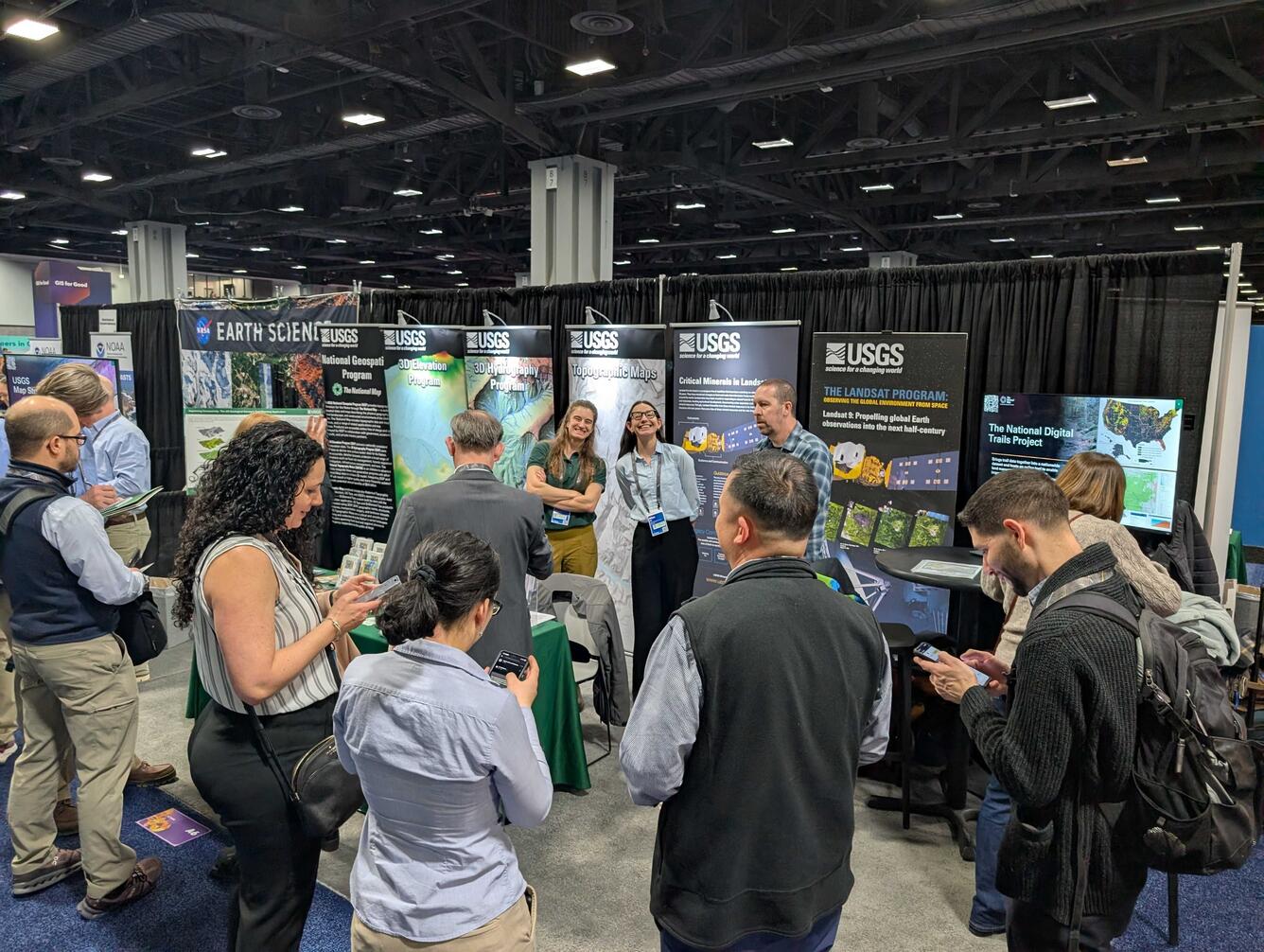 USGS employees smile while standing behind a booth at a conference