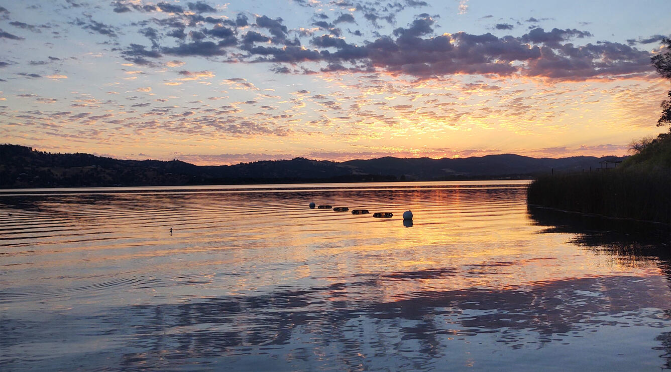 Pink and purple clouds at sunset reflected on lake water